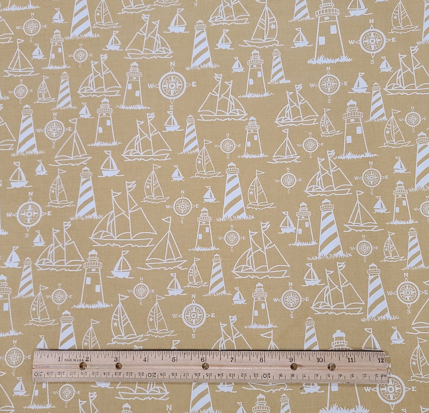 Marcus Brothers Textiles Inc - Golden Tan Fabric / White Lighthouse, Sailboat and Windrows Pattern.